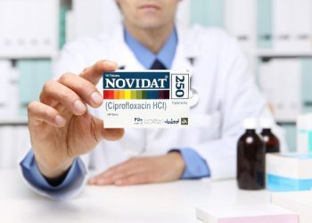Doctor hand showing novidat tablet box at hospital office Desktop.